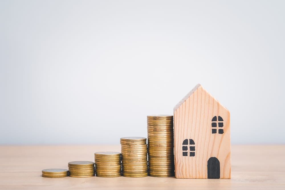 an image of stacks of coins next to a model of a house to denote a story about stamp duty