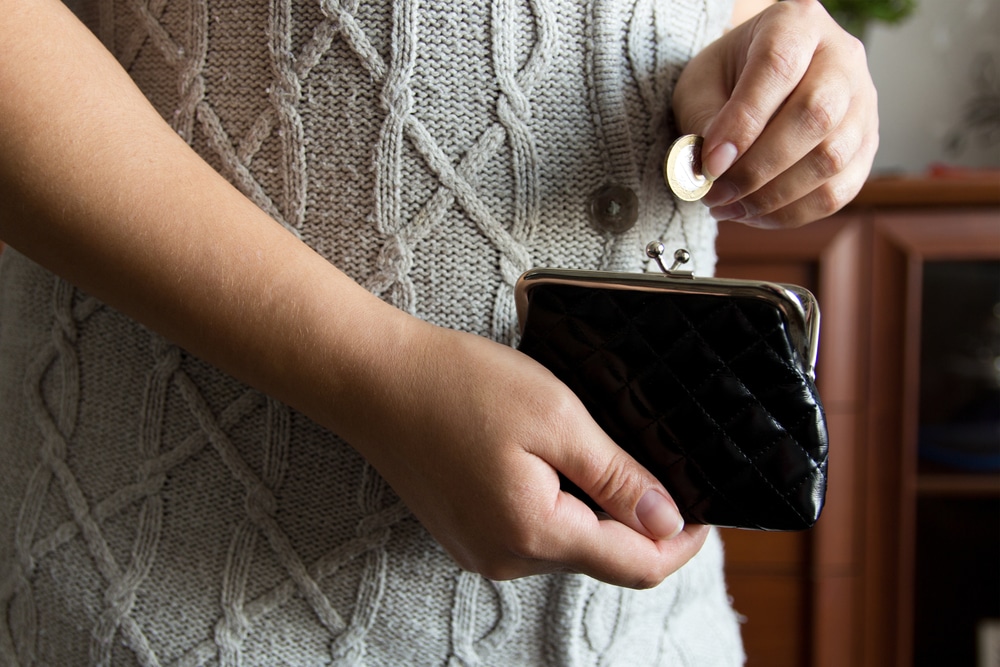 Woman holding coins to denote the rising number of people in poverty