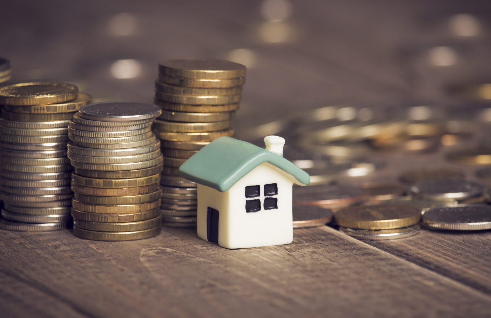 A picture of coins and a model house for a Propertymark story about housing market activity