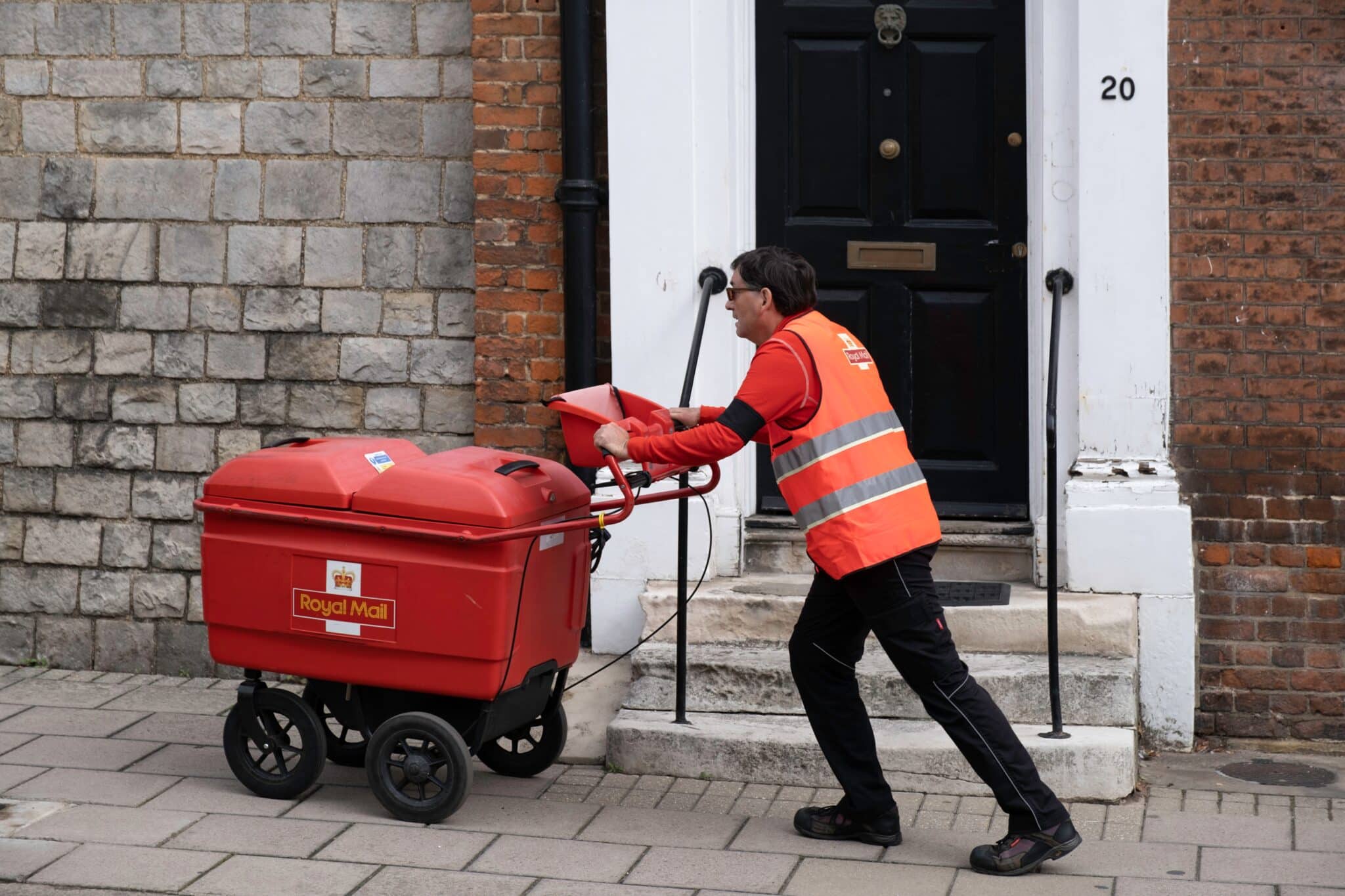 A postal worker pushing a trolley as postal service second-class deliveries to be cut