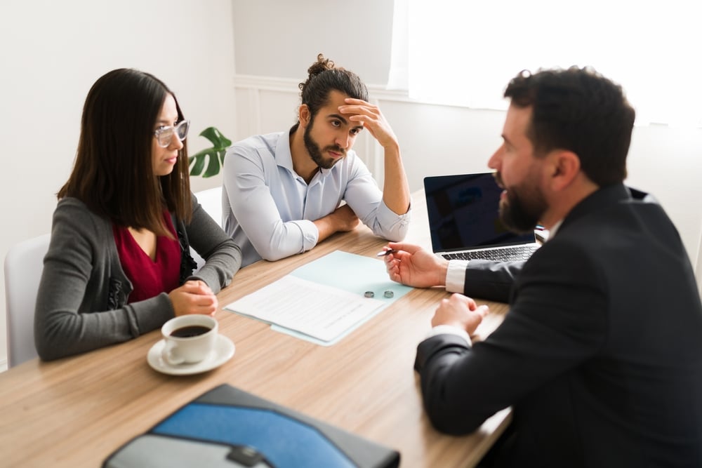 A stressed couple in a meeting with a lawyer to denote a tory on unregulated legal firms