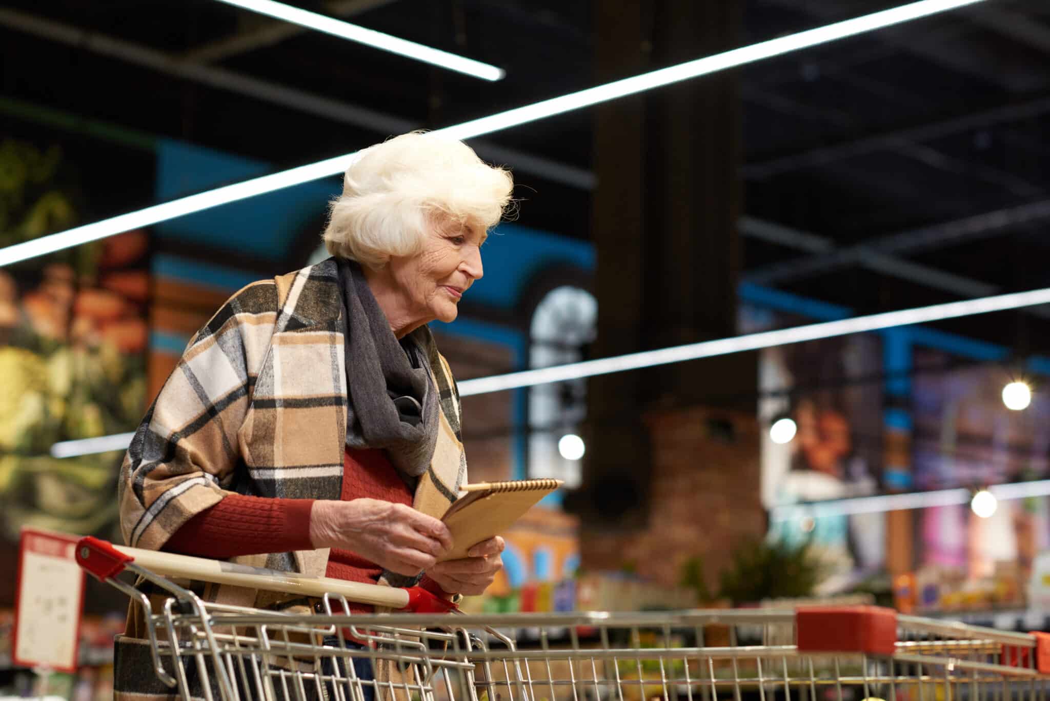 A pensioner pushing a trolley in a supermarket