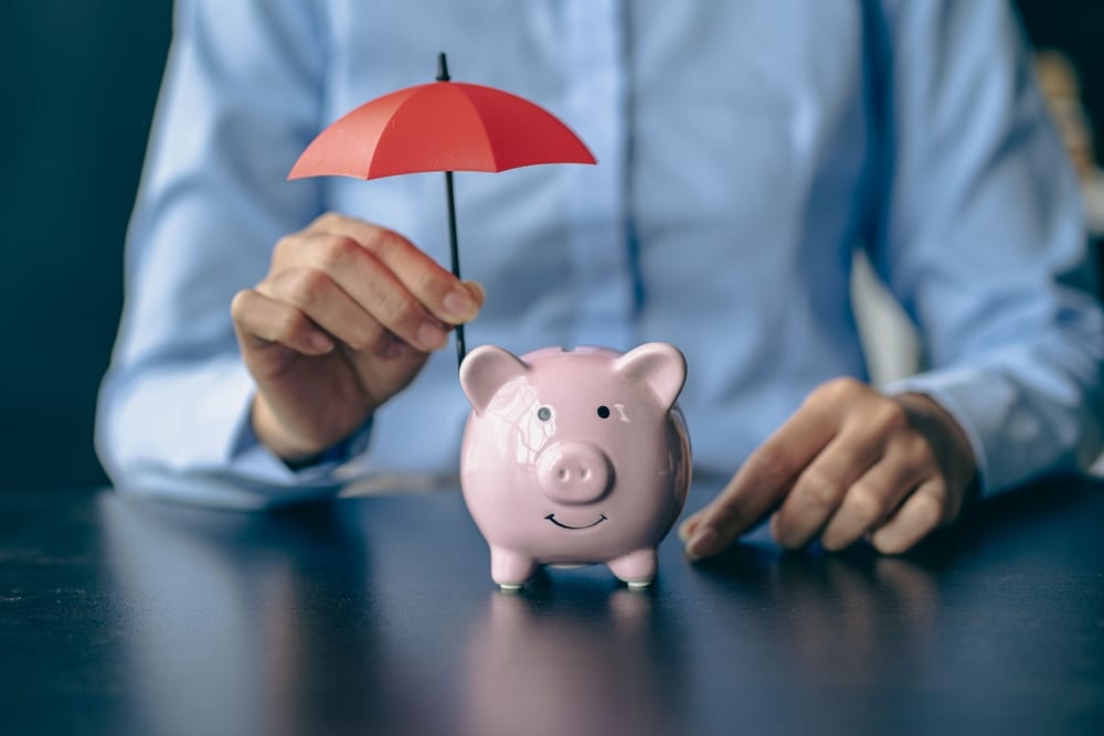 an umbrella above a piggy bank to denote a story on how to protect your finances